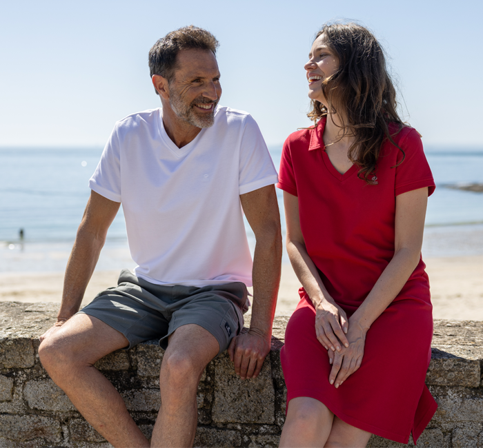 Man and woman sitting by the sea wearing organic cotton clothes