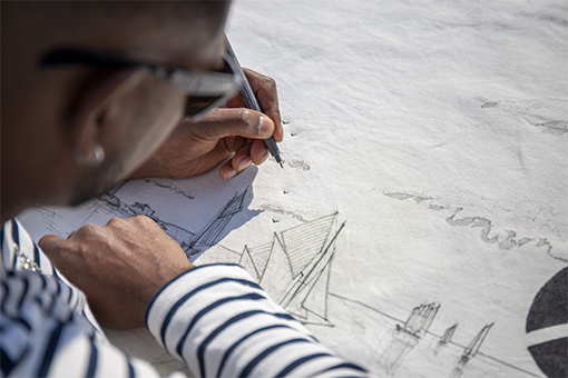 Romuald Nio en train de dessiné sur la vareuse greige